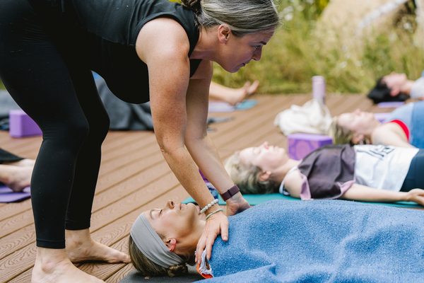 autumn adams preparing a student for shavasana and yoga nidra during an outdoor women's yoga retreat