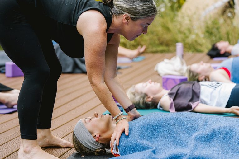 autumn adams preparing a student for shavasana and yoga nidra during an outdoor women's yoga retreat