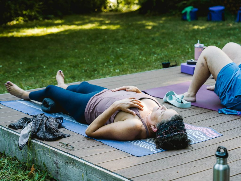 women resting in savasana during a guided yoga nidra practice outdoors on retreat