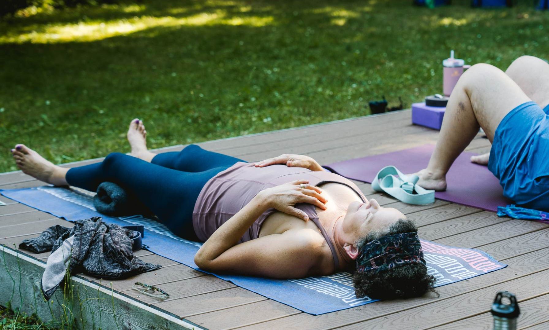 women resting in savasana during a guided yoga nidra practice outdoors on retreat