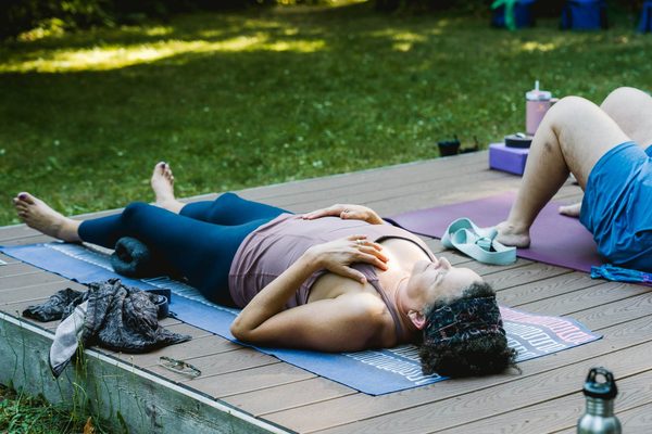 women resting in savasana during a guided yoga nidra practice outdoors on retreat